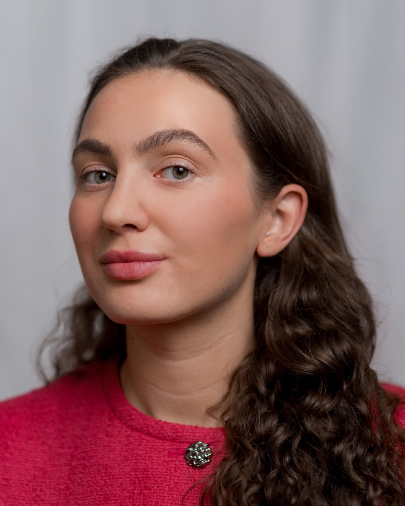 Verzorgde studioheadshot van een donkerharige artiest in het roze