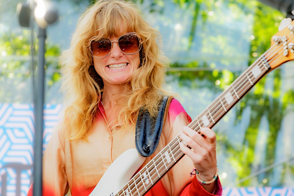 A bass player smiles on the outdoor stage.