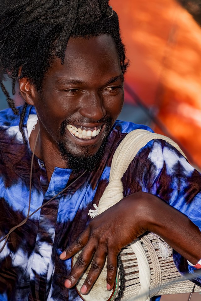 A percussionist smiles while holding his drum.