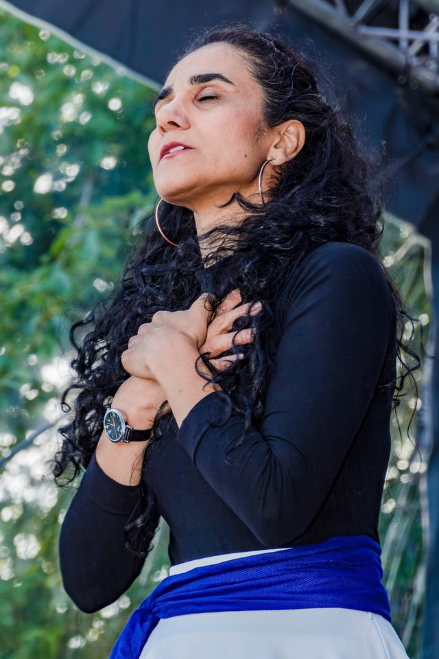 A performer pauses with one hand against her chest.