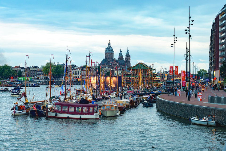 Boats fill the Amsterdam harbour at dusk.