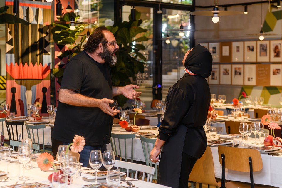 Two people share a conversation beside the tables before dinner.