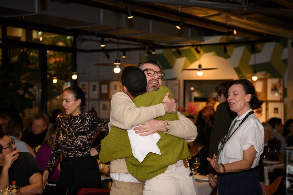 Two guests embrace in the dining room.