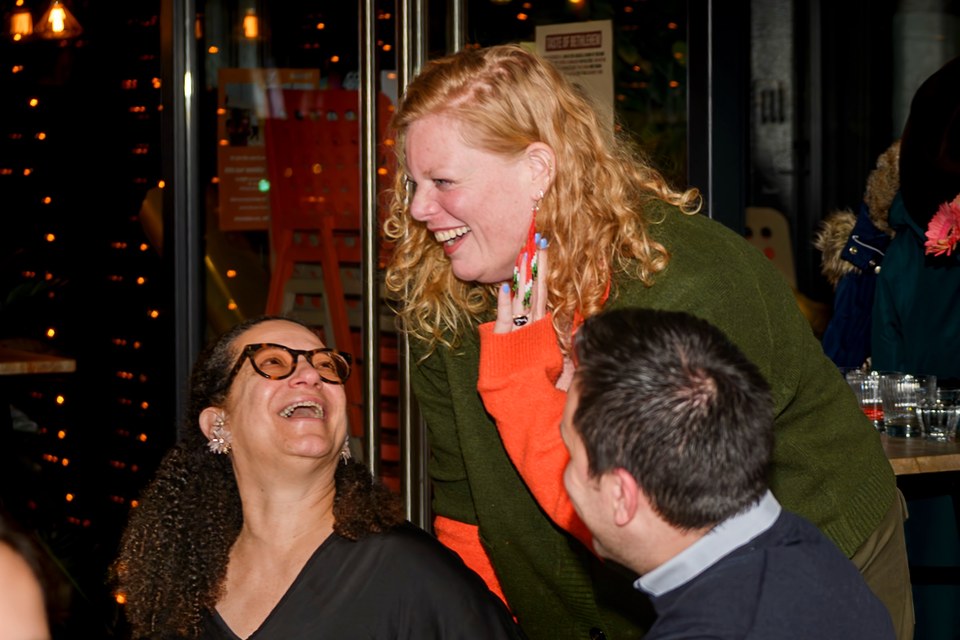 Guests laugh together beside the dinner table.