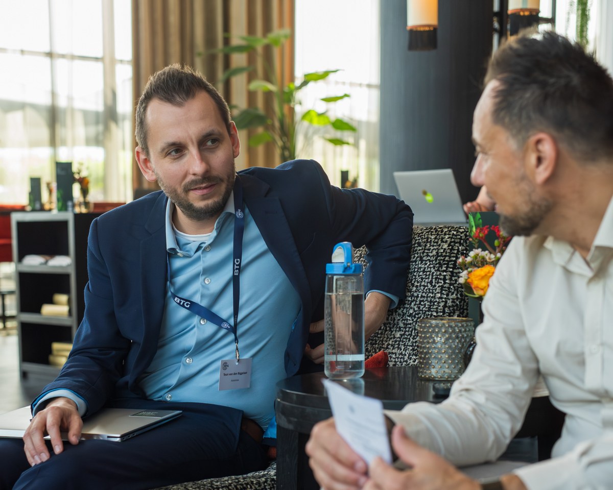 Two men talk across a small table before the presentations.