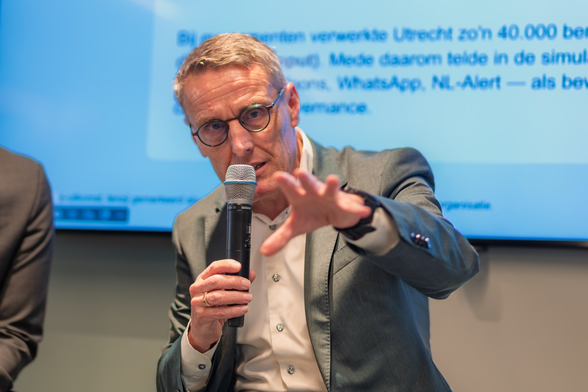 A speaker gestures towards the audience while holding a microphone.