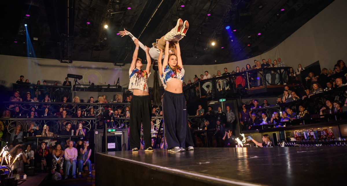 Dancers lift a performer above the runway as the audience watches.