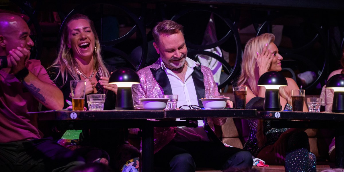 Guests at a table laugh together during the show.