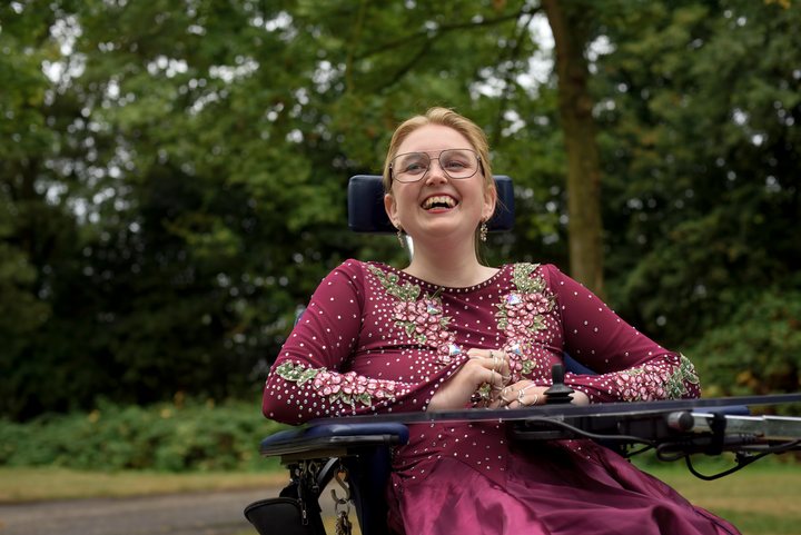 An open, laughing portrait of a woman in a magenta dress.