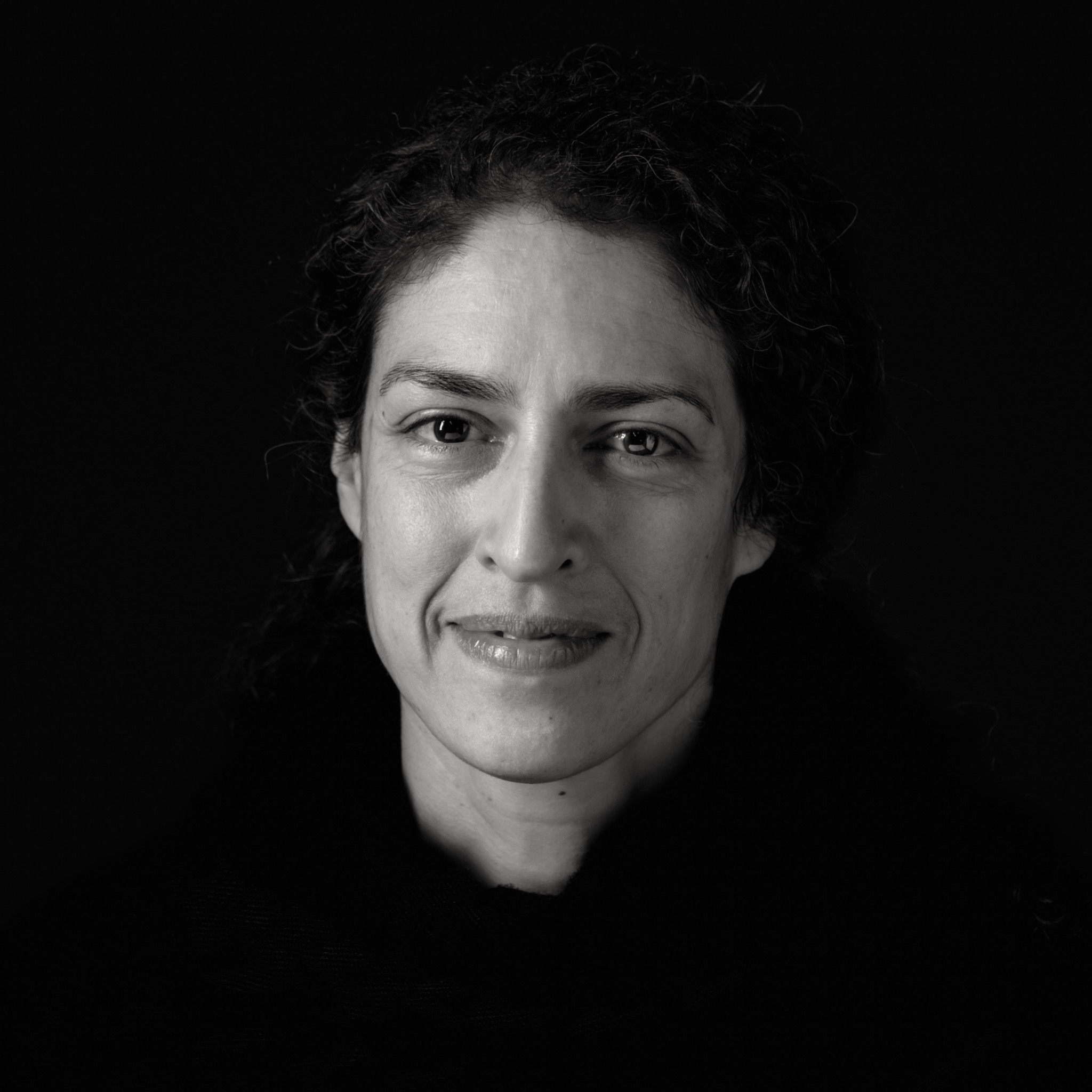 Zwart-wit headshot van een vrouw met donker krullend haar