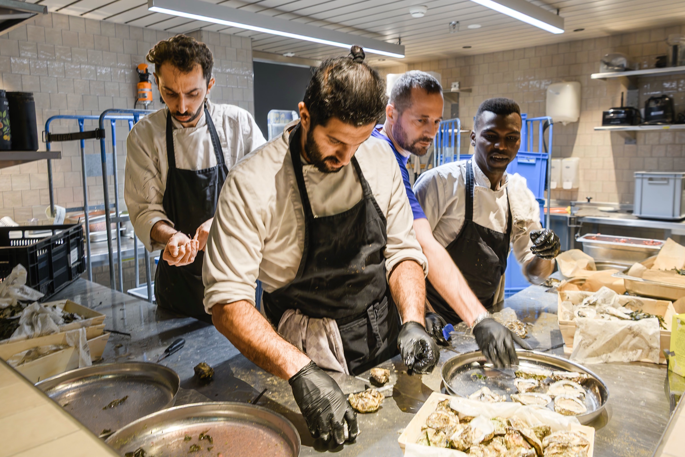 Chefs in white jackets and dark aprons preparing shellfish together at A Beautiful Mess