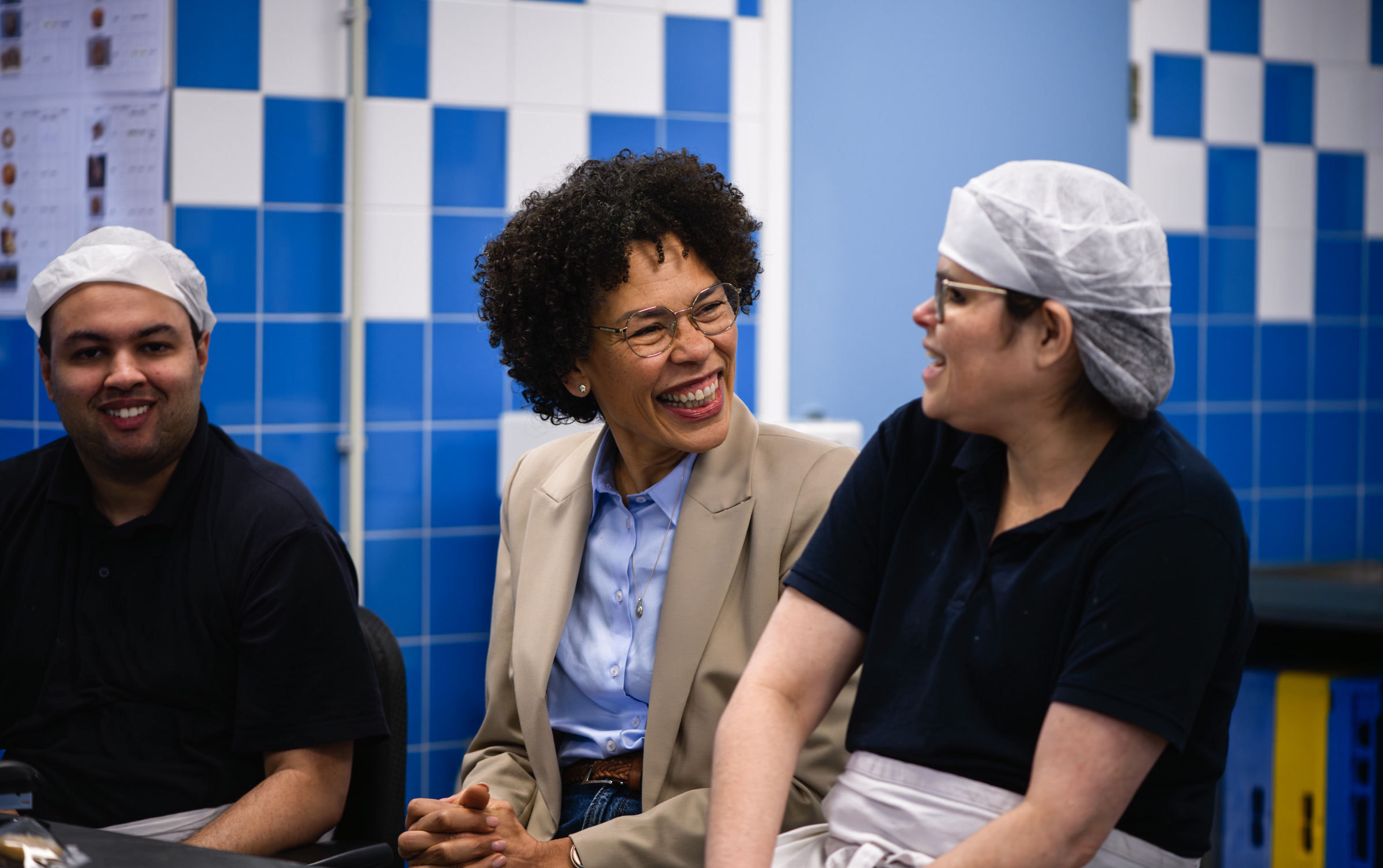 A woman laughing with two colleagues in their kitchen