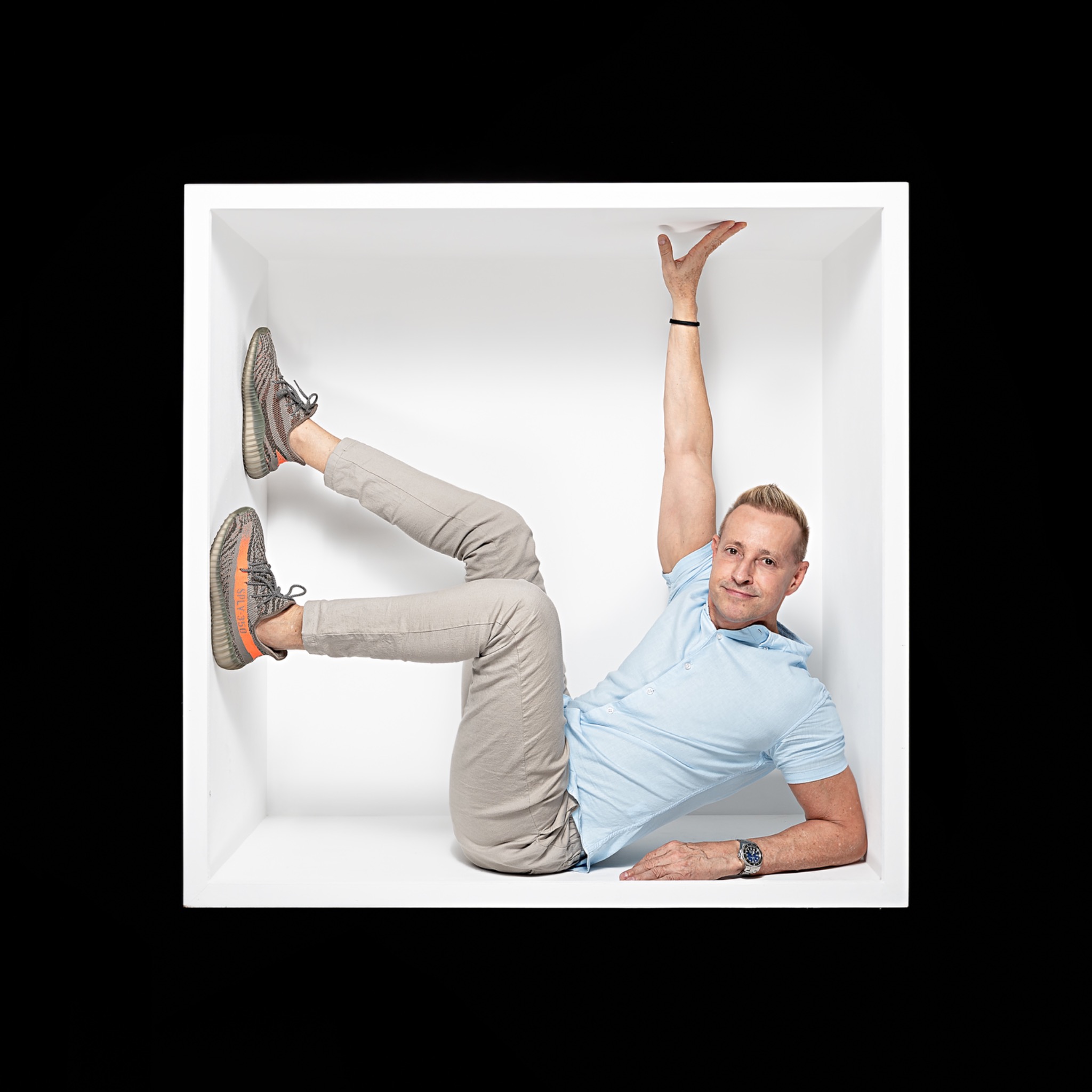 Man balancing playfully inside a white box