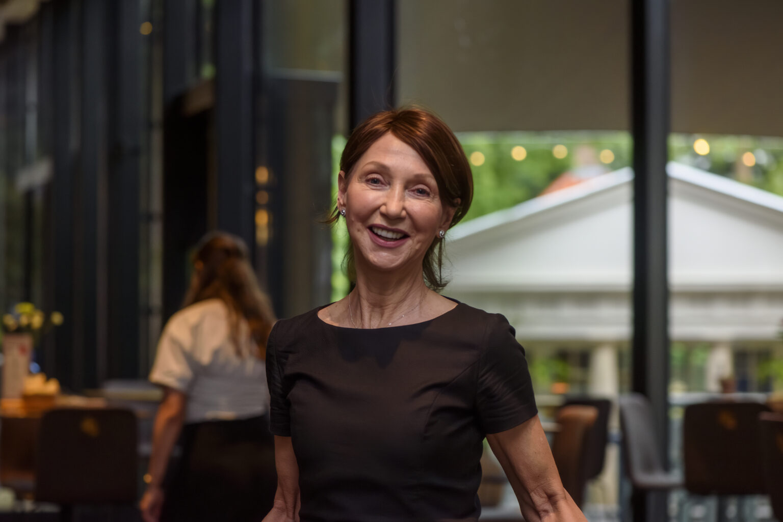 A smiling portrait of a woman in a black dress at the anniversary celebration.